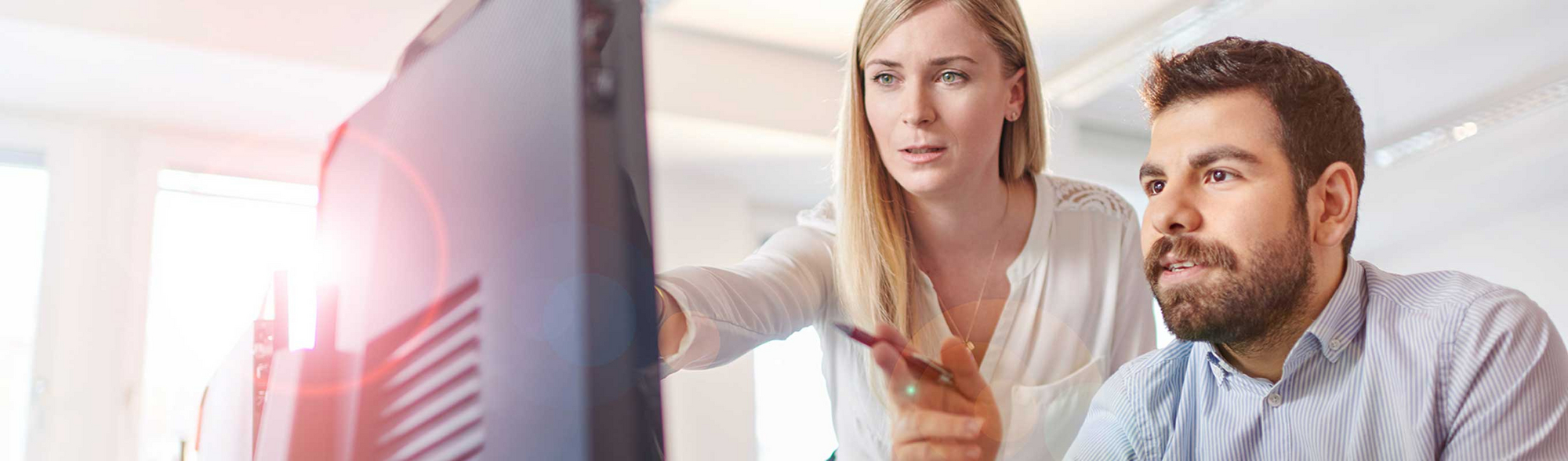 One of our supervisors explains a task to a new employee in front of a screen.