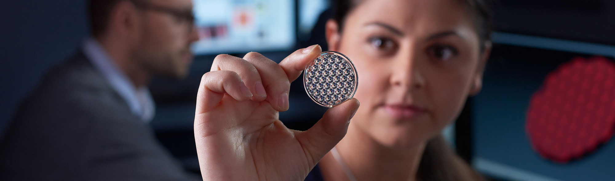 An employee holds a lens and looks through it.