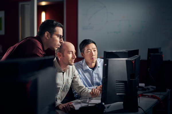 Three Employees sit in front of a screen and work with our software.