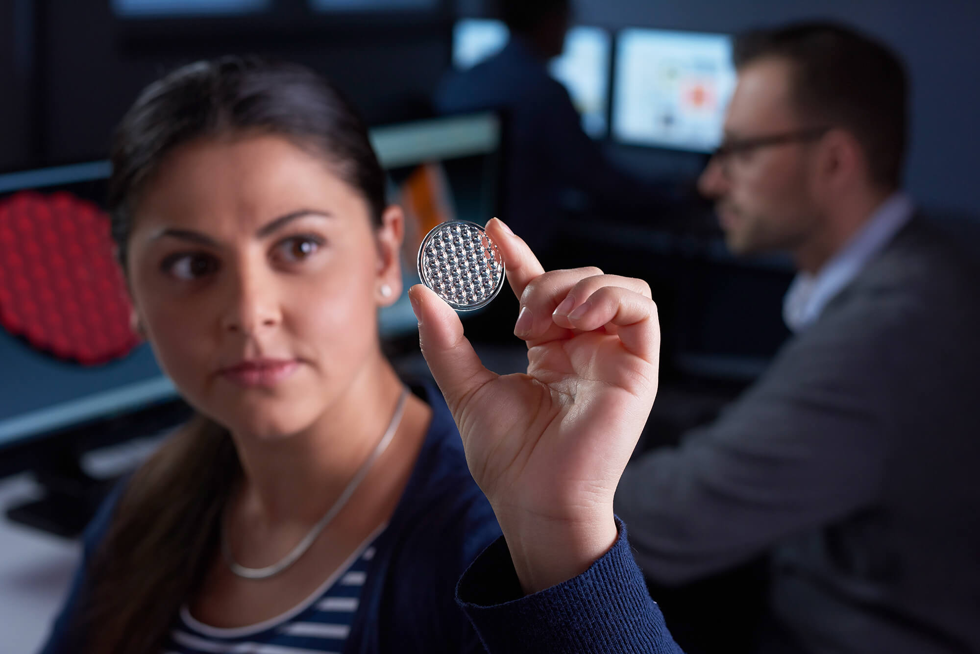 An employee holds a lens and looks through it.